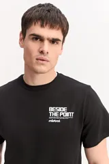 Remera de manga corta color beige, con estampa en la espalda que incluye un paisaje marino de atardecer y texto.