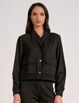 Camperita tipo bomber color beige claro, con cuello redondo acanalado, cierre frontal con broches metálicos y bolsillos delanteros con tapa. Los puños y el bajo son acanalados.