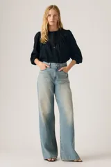 Jeans de corte recto y tiro alto, con diseño de pierna ancha y acabado lavado en tono celeste claro. Presentan cierre frontal con botón y cremallera, además de bolsillos laterales y traseros.