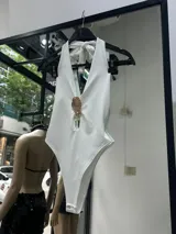 Body negro con escote halter, abertura en el pecho con detalle de aplique dorado y corte cavado.