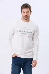 Remera de algodón de manga larga color azul marino, con cuello redondo y estampado frontal en tonos celestes y dorados que dice "Celebrating All Good Things Legacy Brand Since 1972" y "Live a life that you would relive".