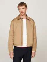 Campera Tommy Hilfiger modelo Ivy, color beige, de corte regular, confeccionada en algodón. Tiene cuello inglés, cierre de cremallera, dos bolsillos diagonales en la cintura, puños con botón y logo de la marca bordado en el pecho.