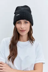 Gorro tipo beanie de punto grueso color amarillo pastel, con vuelta en el borde y etiqueta pequeña con logo en el frente.