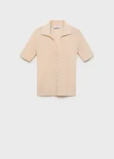 Jersey de punto fino color beige, con cuello camisero, manga corta y cierre frontal con botones pequeños. Diseño entallado de canalé.