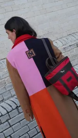 Mochila pequeña color borgoña con detalles en cuero marrón y aplique metálico de un caballo. Tiene manija superior y correas traseras regulables.