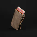 Billetera tipo tarjetero de cuero marrón oscuro con efecto envejecido y costuras visibles. Cuenta con un mecanismo de expulsión de tarjetas y clip para billetes.