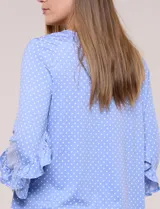 Blusa celeste con estampado de lunares blancos, cuello en V y mangas 3/4 terminadas en volados.