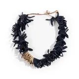 Collar de diseño artesanal compuesto por múltiples piezas pequeñas en forma de pétalos de color negro, con una sección destacada de piezas en tono dorado. Cuenta con un cierre ajustable mediante cordón y botón metálico.