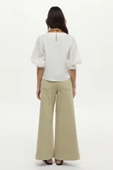 Blusa de lino blanca con escote redondo y mangas cortas abullonadas con detalles de volados en los puños.