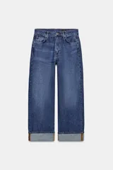 Jeans de tiro medio con corte baggy y pierna relajada. Presenta diseño de cinco bolsillos, cierre frontal con cremallera y botón, y bajo con vuelta marcada.