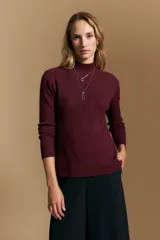 Polera de tejido acanalado color bordó, con cuello alto y diseño geométrico en relieve que estiliza la figura. Presenta un ajuste al cuerpo y mangas largas.