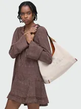 Bolso tipo hobo de Marc Jacobs, confeccionado en lona color beige con detalles en cuero marrón. Presenta el logo de la marca bordado en el frente y una correa de hombro integrada.