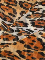 Bufanda rectangular de tela fina con estampado de leopardo en tonos marrones, negros y beige.