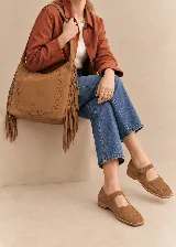 Zapato tipo guillermina de cuero color marrón, con tira en el empeine y hebilla metálica, detalle de costuras decorativas alrededor de la puntera cuadrada y suela plana.