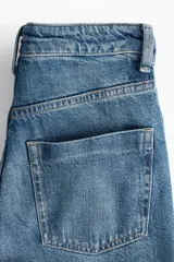 Jean de tiro alto con pierna ancha y corte holgado, confeccionado en denim rígido de cinco bolsillos con cierre y botón.