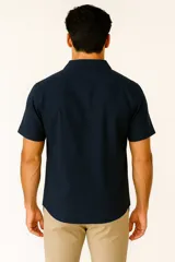 Camisa de lino color verde militar, de corte holgado, con cuello tipo solapa, botones frontales y manga corta.