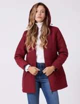 Campera capitoneada de largo midi en color bordó, con diseño de rombos en el cuerpo y mangas, y costuras diagonales en los laterales. Cuenta con cierre frontal, capucha desmontable con interior suave y panel entallado en la cintura.
