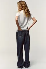 Camiseta blanca de manga corta y cuello redondo, con aplicación de organza y texto negro a contraste en el pecho.