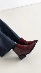 Bota corta de cuero con textura tipo reptil y paneles de gamuza en tono marrón oscuro. Presenta un diseño de punta cuadrada, cierre lateral y un taco cuadrado de madera.