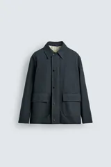 Chaquetón de corte relajado confeccionado en tejido técnico con mezcla de algodón. Presenta cuello solapa, cierre frontal con cremallera oculta por solapa con botones a presión, bolsillos de plastrón con solapa en la cadera y forro interior a contraste.