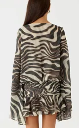 Vestido corto con estampado animal print tipo zebra, escote en V cruzado, mangas largas amplias y cintura fruncida elastizada con falda con volados.