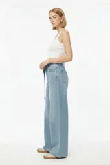 Pantalón jean celeste de tiro medio y corte ancho, con presillas, bolsillos delanteros y traseros, e incluye un cinturón largo del mismo material con hebilla metálica.
