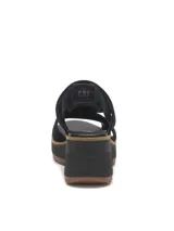 Sandalias de gamuza color negro, con taco alto y plataforma chunky con suela dentada de goma marrón. Presentan diseño con recortes laterales y tira ajustable en el talón.