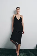 Vestido midi de color negro, con escote en pico y tirantes finos cruzados en la espalda.