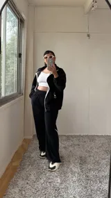 Pantalón de jogging negro de plush, con elástico en la cintura, bolsillos laterales y cinta con logo a lo largo de la pierna.