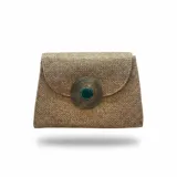 Bolso tipo sobre color tostado de yute de algodón, con solapa y un llamativo detalle circular metálico en el centro que presenta una piedra verde esmeralda.