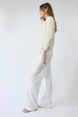 Chaqueta de punto color negro, con escote en pico, manga larga y cierre frontal con botones dorados. Presenta un diseño con bajo asimétrico.