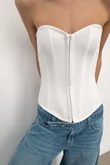 Top tipo corset de escote corazón y hombros descubiertos, con varillas interiores para estructura. Presenta cierre frontal con ganchos metálicos y ajuste en la espalda mediante cordones cruzados.