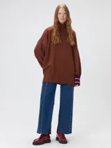 Pullover de cuello tortuga color marrón, de corte holgado y diseño básico. Presenta puños acanalados en contraste de color bordó con líneas horizontales celestes.