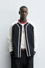 Chaqueta de corte relajado con diseño color block, cuerpo en color azul marino y mangas en color blanco. Presenta cuello redondo, cierre frontal con botones y puños de rib a rayas.