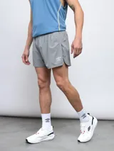 Short de entrenamiento Umbro modelo Chase, color gris, confeccionado en tejido elástico con aberturas laterales y logo estampado en la pierna.