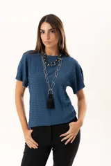 Blusa de silueta relajada y cuello redondo, confeccionada en tela liviana con textura. Presenta mangas cortas y una caída suelta.