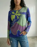 Remera de manga larga con cuello redondo, confeccionada en jersey suave con un diseño estampado de líneas orgánicas en tonos azul, verde y violeta. Presenta un corte recto y cómodo, ideal para uso versátil.