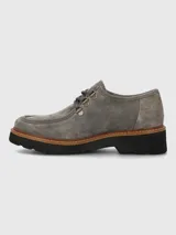 Zapato de estilo robusto confeccionado en descarne color gris, con diseño de cordones, ojales metálicos y suela gruesa de goma en color negro con detalle de vira en tono madera.