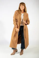 Tapado largo color camel, con solapas clásicas, cierre frontal con lazo ajustable y detalles de trabillas en los puños.