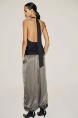 Top negro de tejido satinado con cuello halter y lazada. Cierre lateral con cremallera oculta.