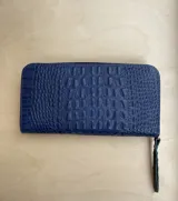 Billetera de charol color cereza con textura tipo cocodrilo y cierre perimetral con cremallera.