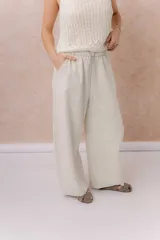Pantalón de denim liviano color beige, de calce amplio y relajado con pierna recta. Cuenta con cintura elastizada, cordón regulable, bolsillos laterales y costuras delanteras verticales que estilizan la silueta.