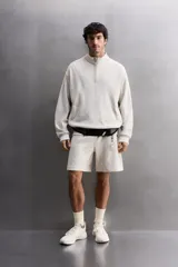 Sudadera gris claro de algodón con interior de rizo, cuello alto con cremallera, manga larga, bolsillos laterales y logo estampado en el pecho.