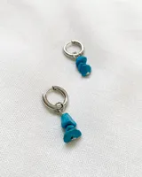 Par de aros colgantes plateados con tres piedras turquesas irregulares.