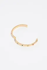 Pulsera rígida tipo esclava de color dorado con cierre de bisagra, decorada con cristales de colores incrustados y letras grabadas en la superficie.