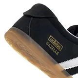 Championes Adidas modelo Gazelle Lo Pro, color negro con las tres tiras laterales en blanco y suela de goma color caramelo. Presenta el logo de la marca y el nombre del modelo en dorado en el lateral.