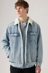 Campera de jean azul claro con cuello y forro de sherpa blanco, cierre de botones frontales, dos bolsillos con solapa en el pecho y dos bolsillos laterales.