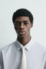 Corbata ancha confeccionada en tejido de seda con diseño de rayas diagonales en tonos beige y gris.
