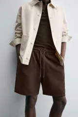 Bermuda de algodón color beige claro, de corte regular fit, con cintura elástica ajustable mediante cordón. Presenta bolsillos laterales y un bolsillo trasero de vivo.