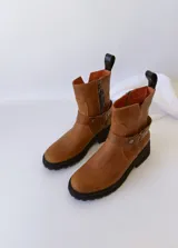 Bota de cuero color marrón con suela de goma negra, cierre lateral y pulsera desmontable con hebilla.